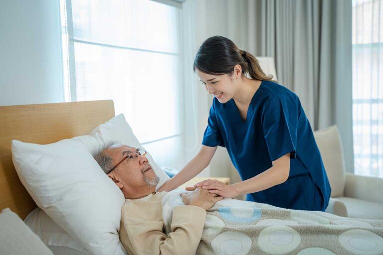 An elderly woman smiling while talking with a caregiver in a comfortable lounge area.