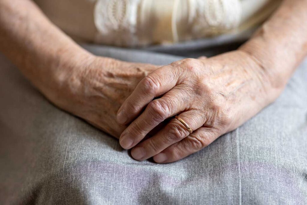 An older adult and family member talk beside a comfortable assisted living room with photos and personal belongings.